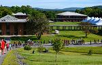 Students walking downhill on a concrete path overlooking a college campus with mountains and green grass in the background